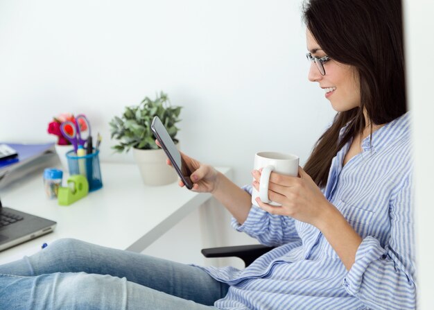 Mujer con la taza usando el teléfono