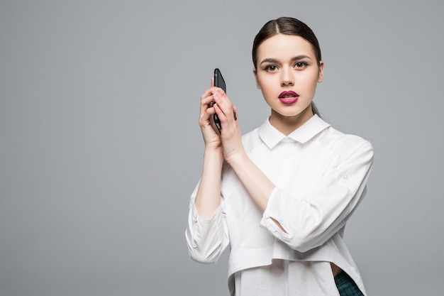 Mujer con un teléfono celular. Aislado en la pared blanca.