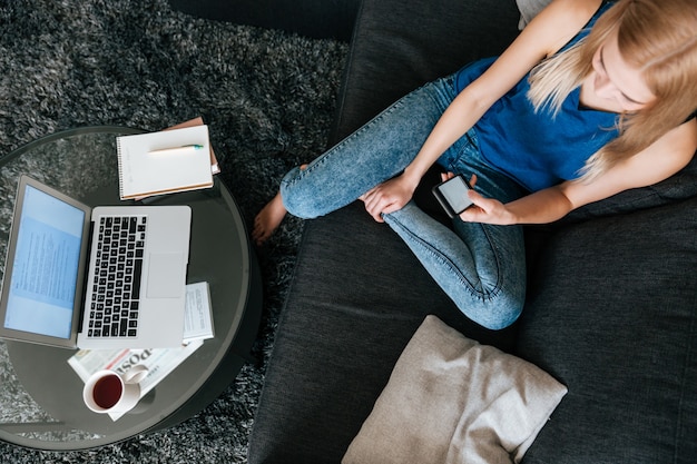 Foto gratuita mujer con teléfono celular y computadora portátil en casa