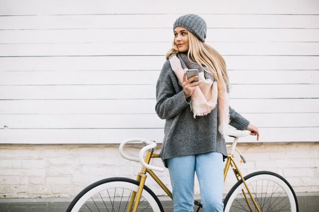 Mujer con teléfono inteligente cerca de bicicleta