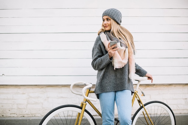 Mujer con teléfono inteligente cerca de bicicleta