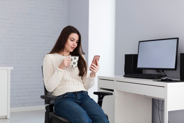 Mujer con teléfono inteligente en la computadora