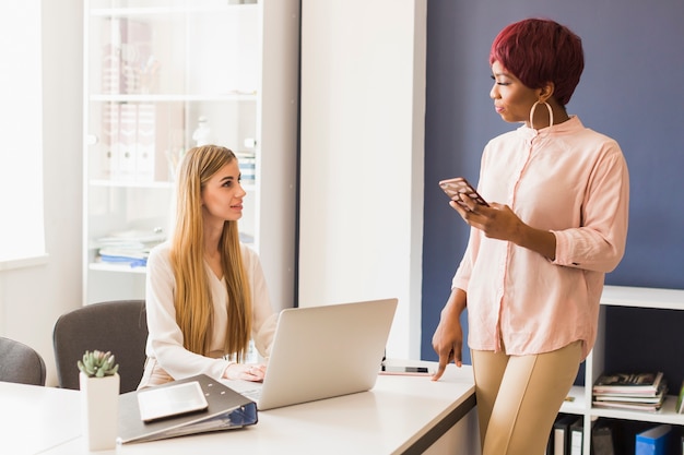 Foto gratuita mujer con teléfono inteligente hablando con un colega