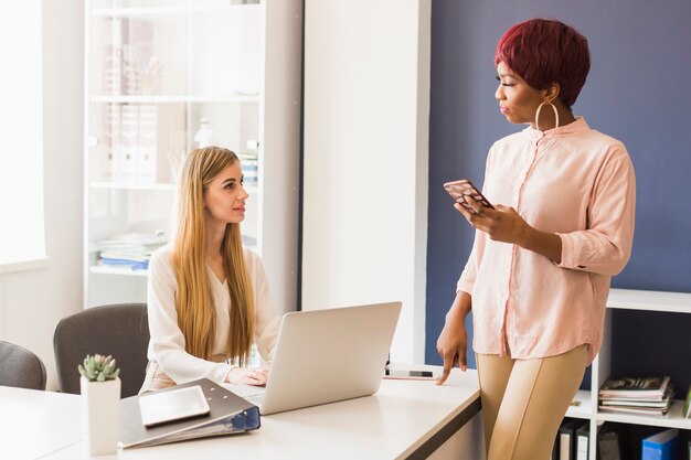 Mujer con teléfono inteligente hablando con un colega