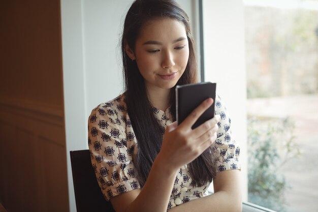 Mujer con teléfono móvil junto a la ventana