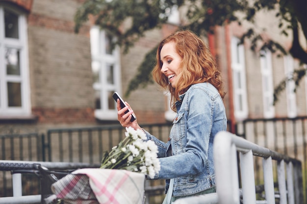 Mujer con teléfono móvil moderno en la ciudad