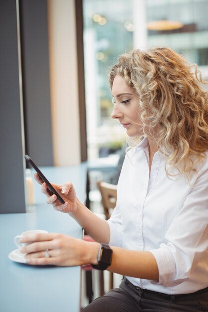 Mujer con teléfono móvil en el mostrador