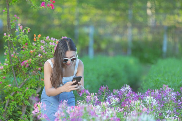 Mujer con teléfono móvil para tomar fotos en el jardín de flores.