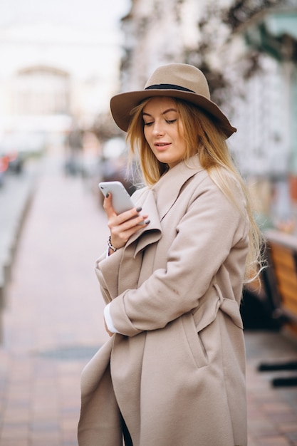 Mujer con teléfono en sombrero fuera de la calle