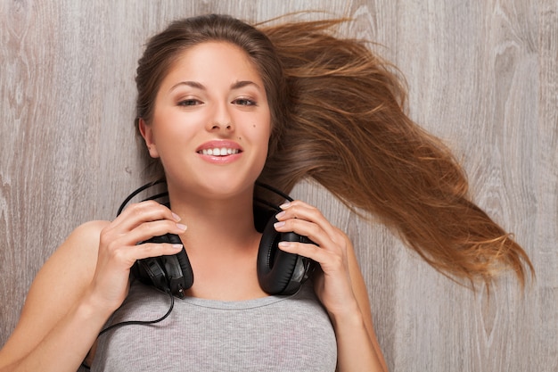 Foto gratuita mujer tendida en el suelo con auriculares