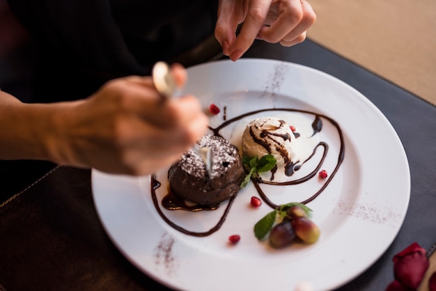 Mujer con tenedor y delicioso postre de chocolate fresco en restaurante