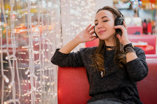 Foto gratuita mujer, tenencia, auriculares, en, cabeza, cerca, luces de navidad