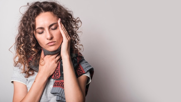 Mujer teniendo frío y gripe contra el fondo gris