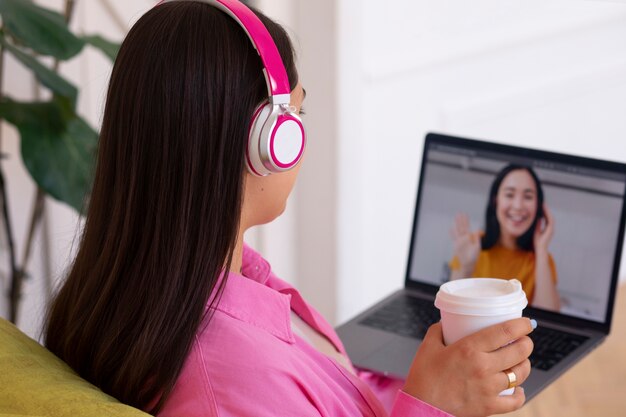 Mujer teniendo una videollamada en una computadora portátil mientras está sentada en el sofá de casa