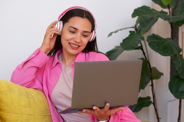 Mujer teniendo una videollamada en una computadora portátil mientras está sentada en el sofá de casa