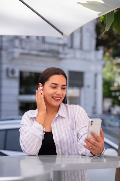 Mujer teniendo una videollamada en un teléfono inteligente mientras está en la ciudad