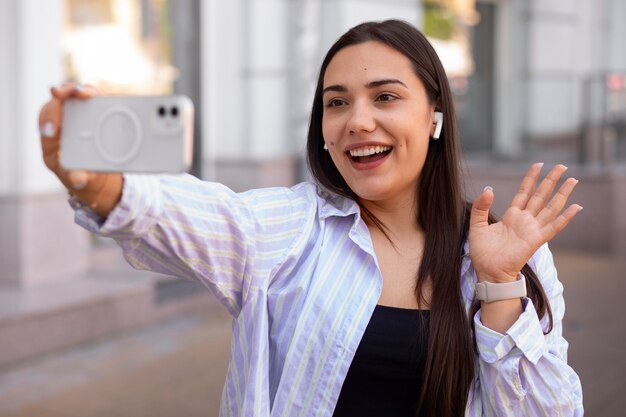 Mujer teniendo una videollamada en un teléfono inteligente mientras está en la ciudad