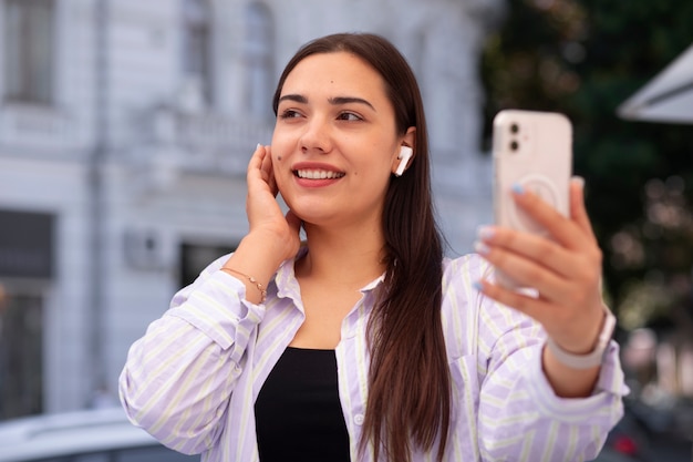 Mujer teniendo una videollamada en un teléfono inteligente mientras está en la ciudad