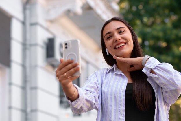 Mujer teniendo una videollamada en un teléfono inteligente mientras está en la ciudad