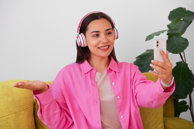 Mujer teniendo una videollamada en un teléfono inteligente mientras está sentada en el sofá de casa