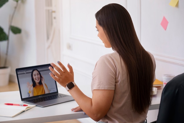 Foto gratuita mujer teniendo una videollamada usando un dispositivo portátil desde casa