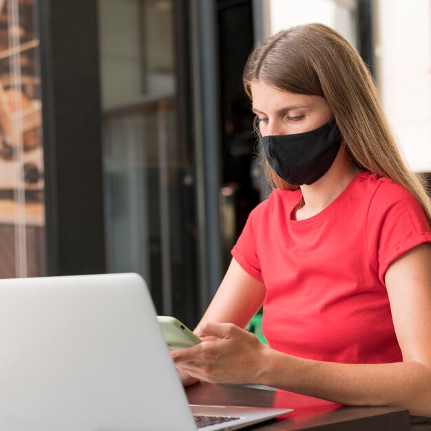 Mujer en terraza trabajando con mascarilla