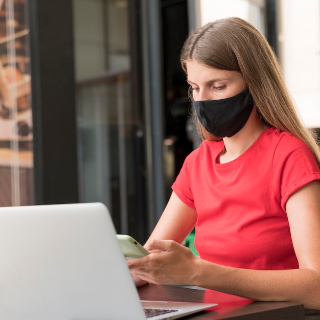 Mujer en terraza trabajando con mascarilla