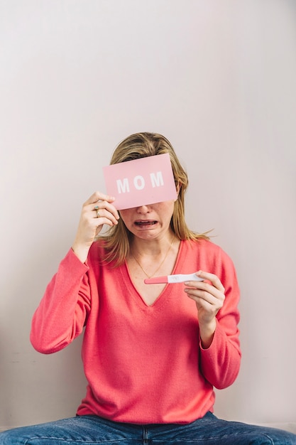 Mujer con test de embarazo y tarjeta