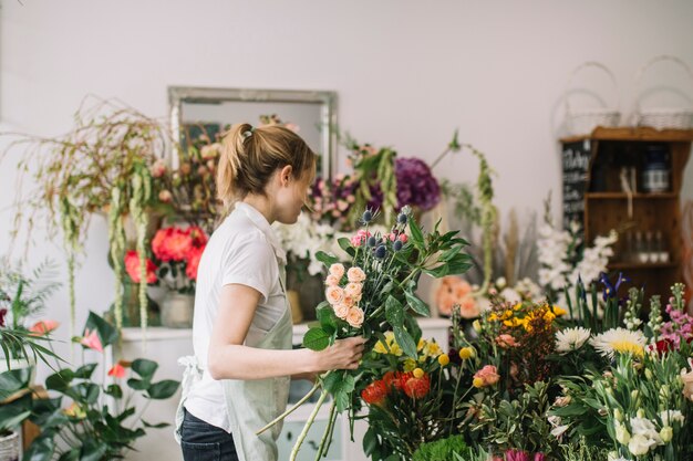 Mujer en tienda de flores arreglando flores