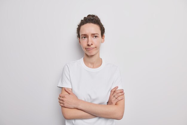 La mujer tiene una expresión de desaprobación nerviosa escéptica mantiene los brazos cruzados vestida con una camiseta casual aislada en blanco disatinada con algo que no le gusta tu opinión