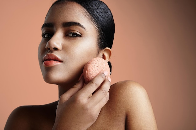 La mujer tiene un tratamiento con una esponja facial rosa konjac