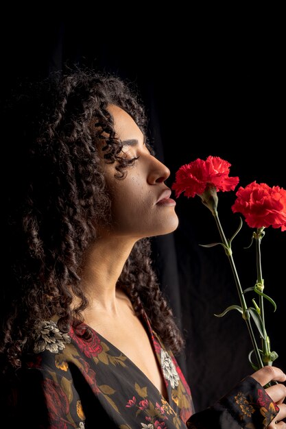 Mujer tierna étnica con flores en la oscuridad