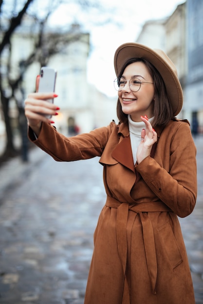 Mujer tierna feliz tomando fotos en su teléfono en un día de otoño afuera