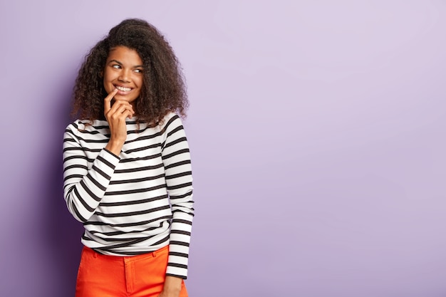 Mujer tímida y optimista tiene una mirada tierna y amigable, corte de pelo afro