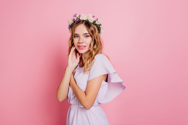 Mujer tímida en traje de verano romántico posando en la pared rosa