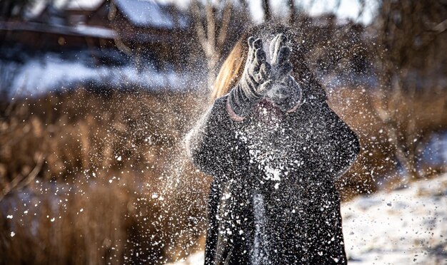 Una mujer tira nieve en un paseo en clima soleado en invierno