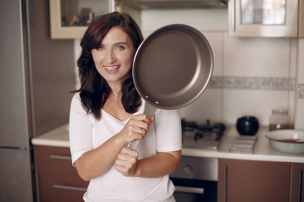 Foto gratuita mujer con tirantes mira a la cámara y sonríe. lady está preparando comida.