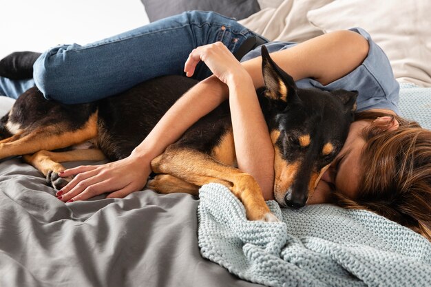 Mujer de tiro completo abrazando a perro en la cama