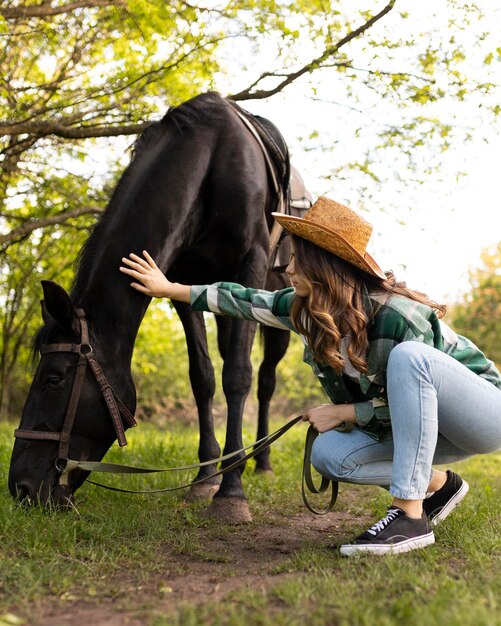 Mujer de tiro completo acariciando a caballo