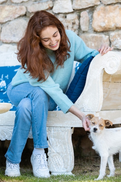 Foto gratuita mujer de tiro completo acariciando lindo perro