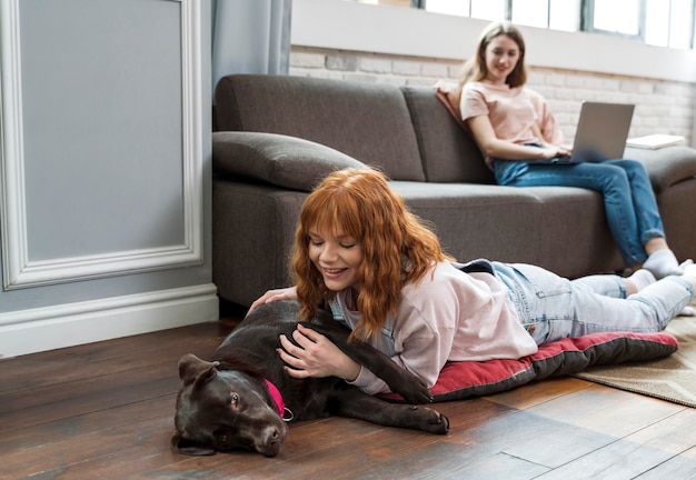 Foto gratuita mujer de tiro completo acariciar a un perro en el piso