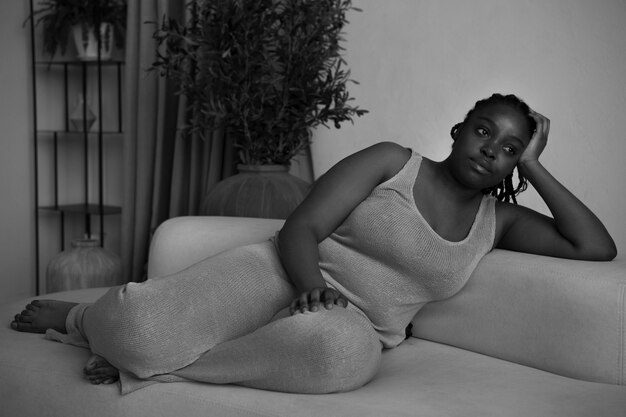 Mujer de tiro completo acostada en el sofá en blanco y negro