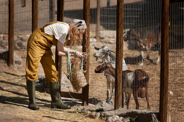 Mujer de tiro completo alimentando cabras