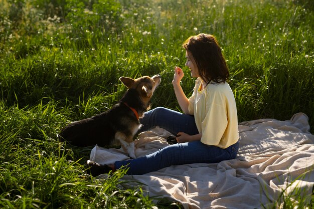 Mujer de tiro completo alimentando perro en la naturaleza