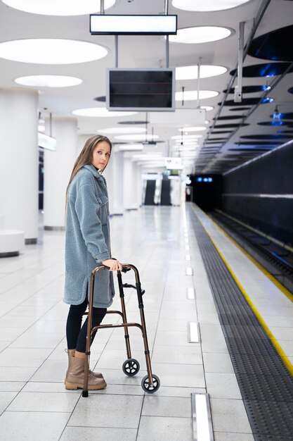 Mujer de tiro completo con andador en la estación de metro