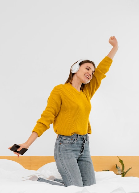 Mujer de tiro completo con auriculares en la cama