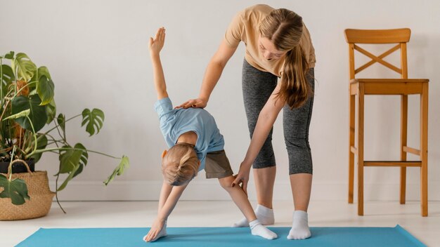 Mujer de tiro completo ayudando a hacer ejercicio para niños