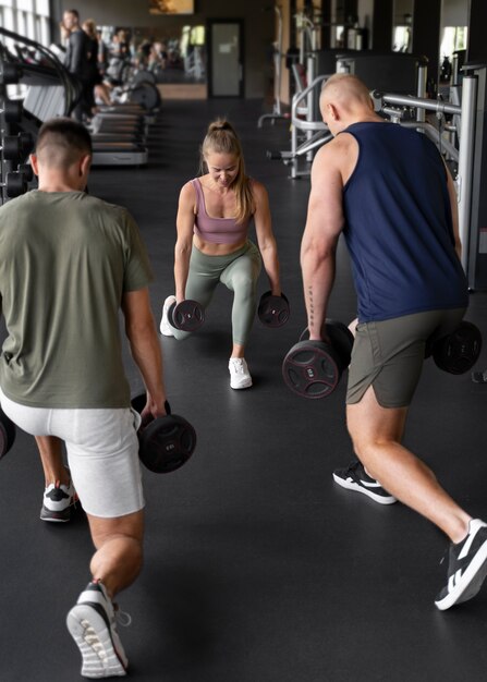 Mujer de tiro completo ayudando a hombres en el gimnasio