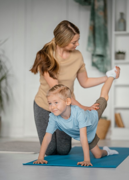 Foto gratuita mujer de tiro completo ayudando a niño a hacer ejercicio