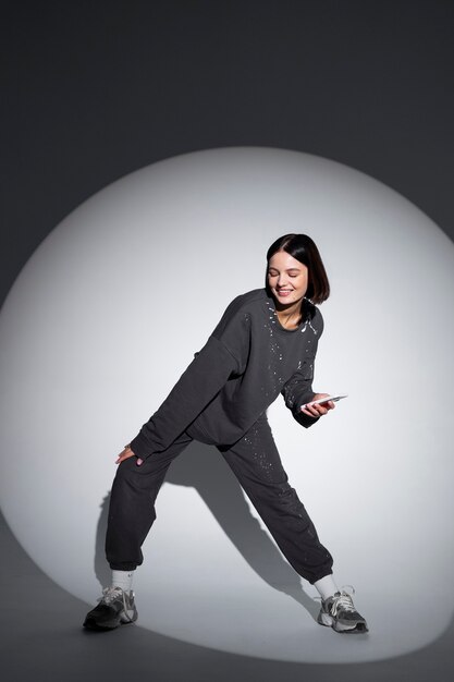 Mujer de tiro completo bailando con teléfono inteligente